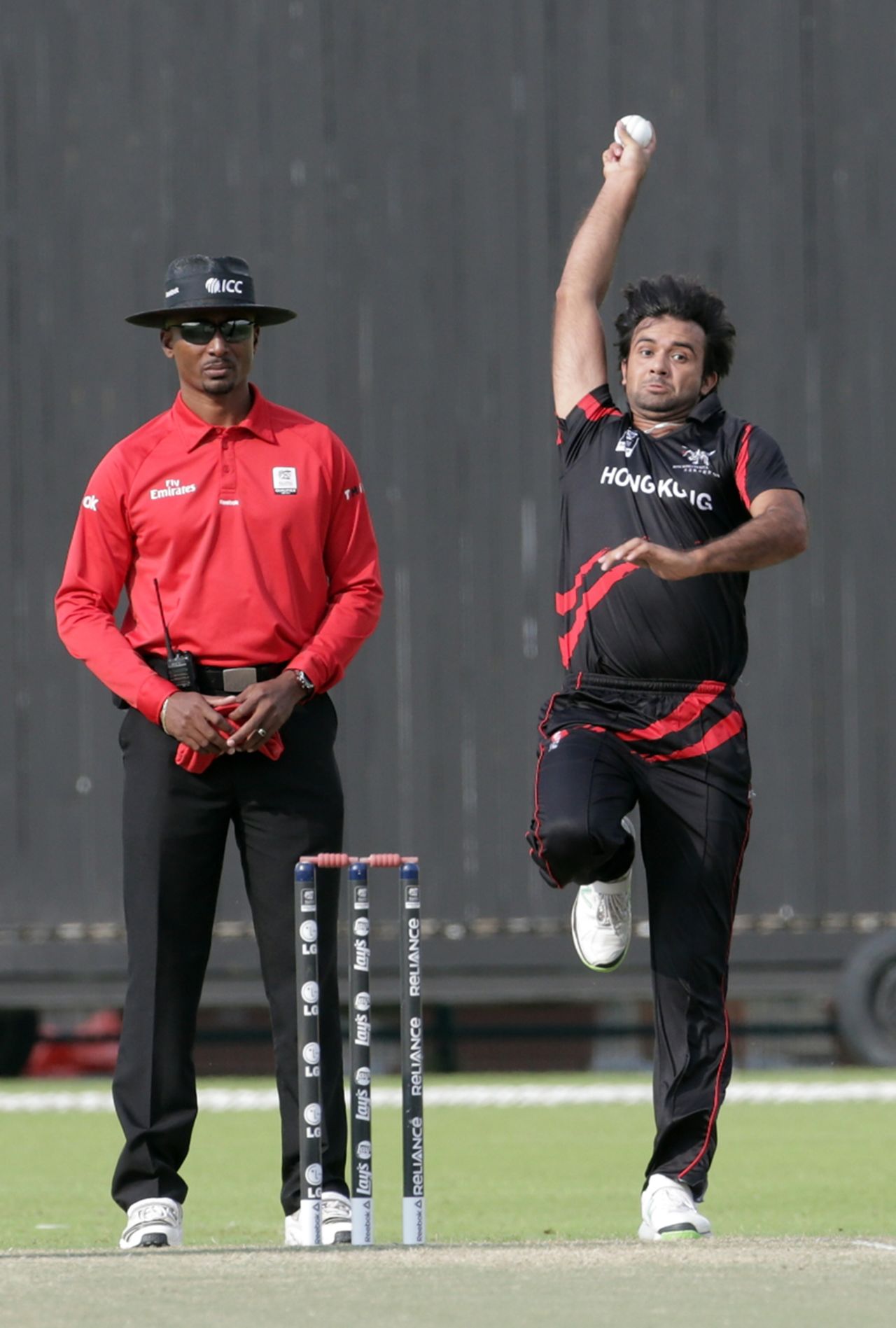 Haseeb Amjad of Hong Kong coming in to bowl along side umpire Gregory Brathwaite during the Ireland v Hong Kong match at the ICC World Twenty20 Qualifiers at the Zayed Cricket Stadium on November 24, 2013 in Abu Dhabi, United Arab Emirates. (Photo by Graham Crouch-IDI/IDI via Getty Images)