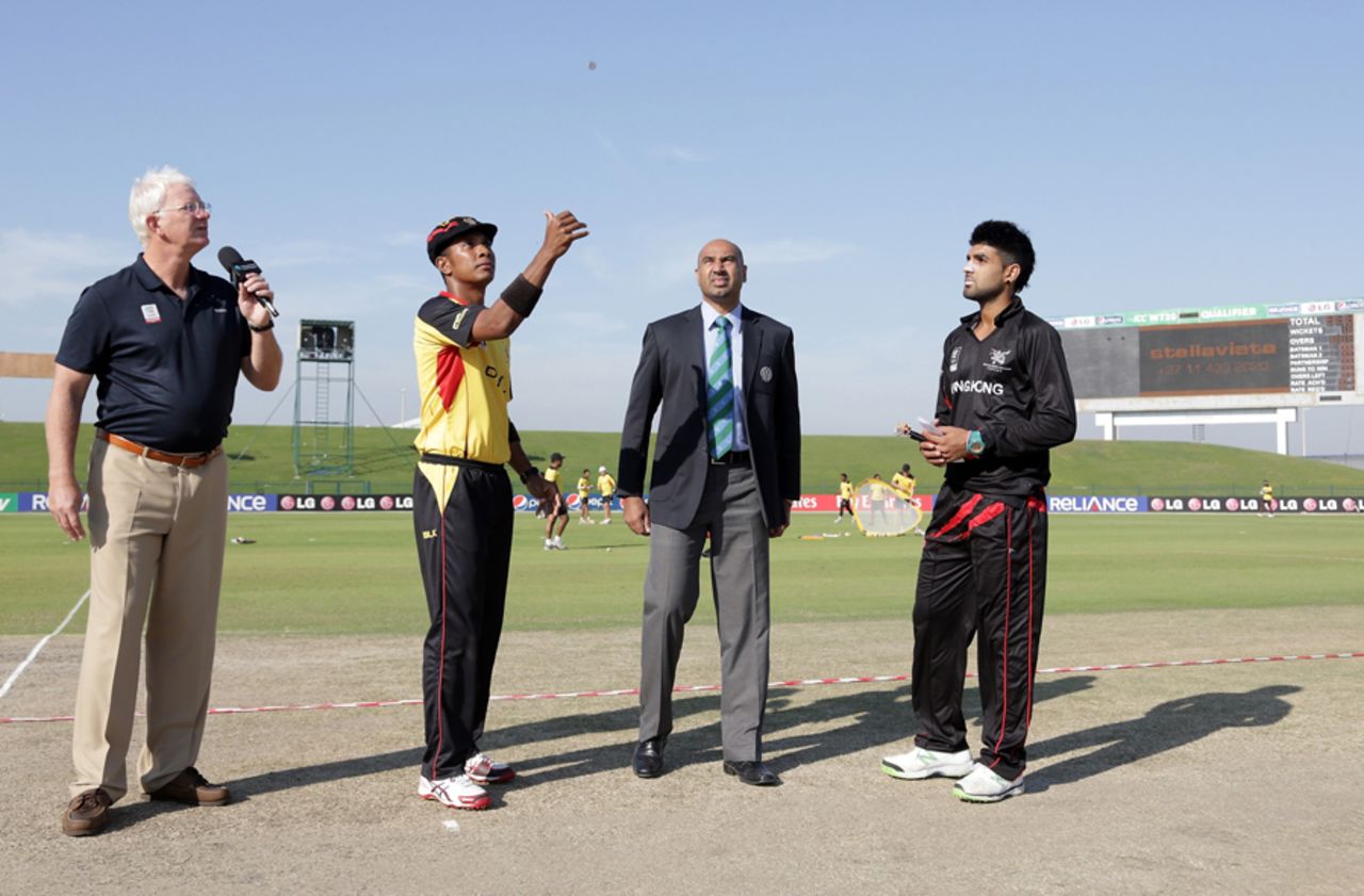 Christopher Amini captain of Papua New Guinea tosses the coin with Waqas Barkat captain of Hong Kong watched by referee Graeme La Brooy and commentator Paul Allott (at left) ahead of the Papua New Guinea v Hong Kong Quarter Final match 64 at the ICC World Twenty20 Qualifiers at the Zayed Cricket Stadium on November 28, 2013 in Abu Dhabi, United Arab Emirates. (Photo by Graham Crouch-IDI/IDI via Getty Images)