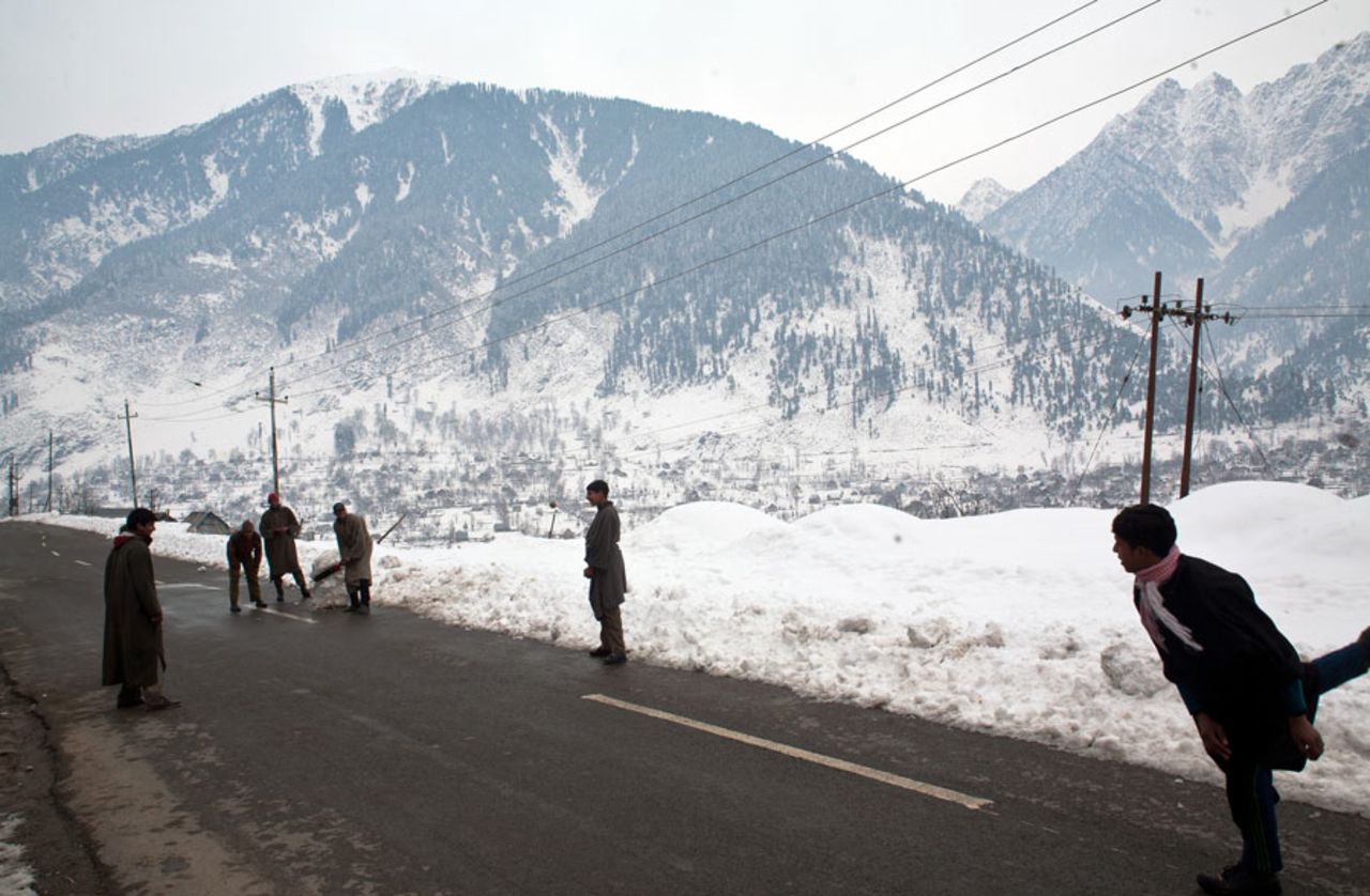 A group of people find time for cricket on a snow-covered highway, Srinagar, January 14, 2014