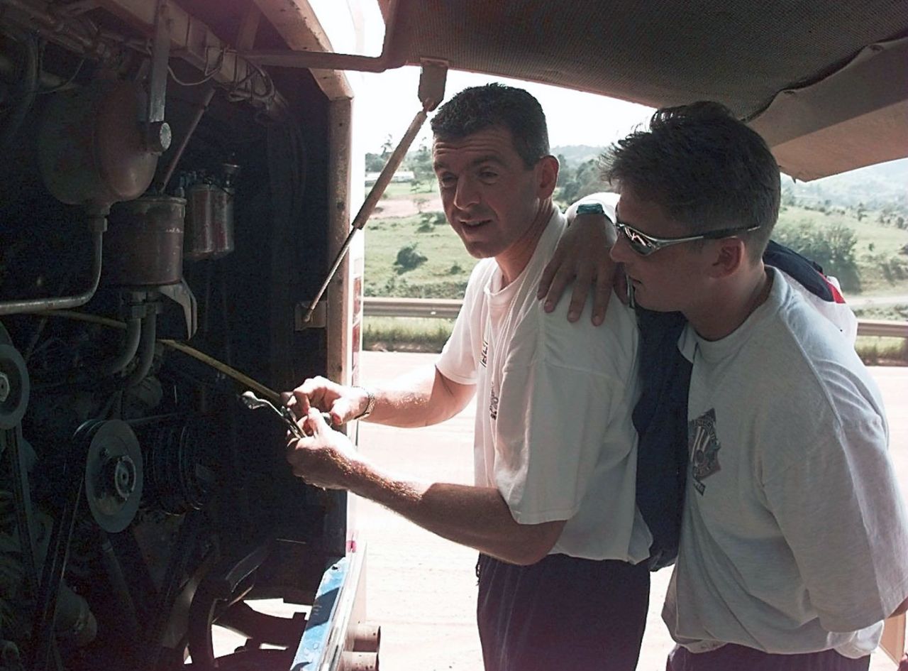 Darren Gough watches England physio Wayne Morton trying to fix their broken down bus, December 20, 1995
