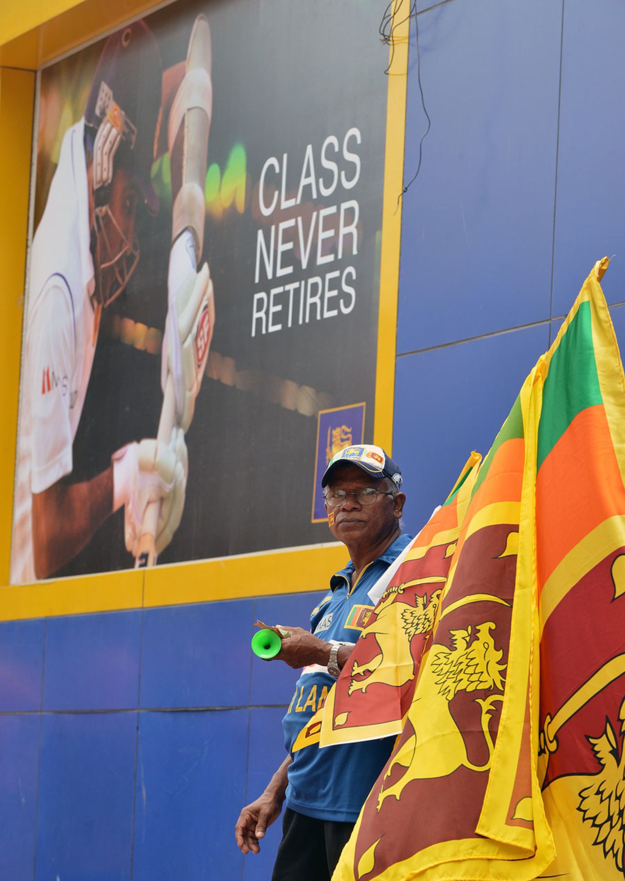 A vendor stands next to a banner celebrating Mahela Jayawardene at the SSC, Sri Lanka v Pakistan, 2nd Test, Colombo, 3rd day, August 16, 2014