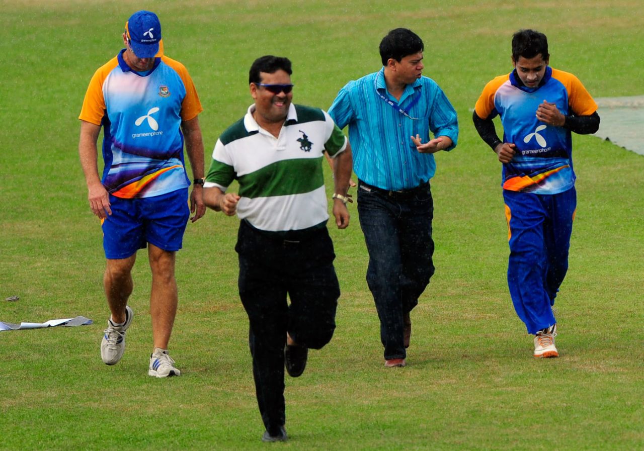 Mushfiqur Rahim, Minhajul Abedin and Akram Khan run to take shelter from the rain, Chittagong, October 17, 2011