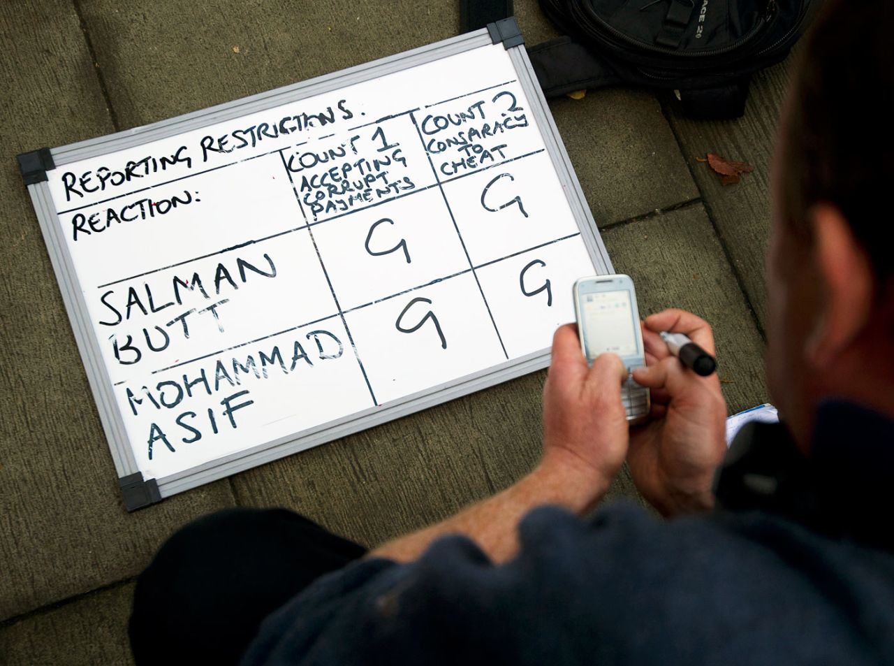 A reporter waits for a text update next to whiteboard indicating guilty verdicts for Salman Butt and Mohammad Asif outside the Southwark Crown Court in London, November 1, 2011