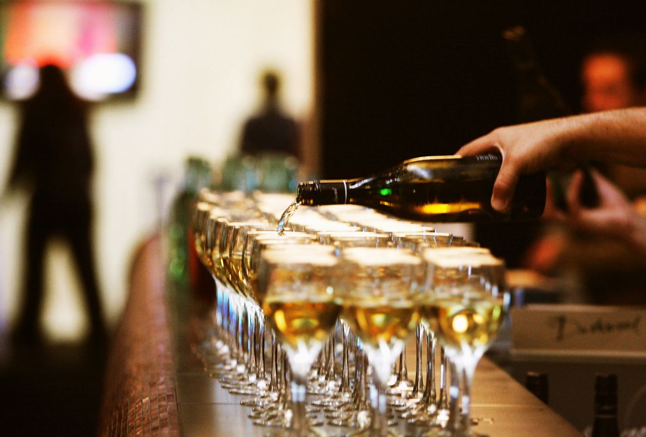 Wine is poured into glasses for guests at a fashion show in Auckland, September 20, 2006