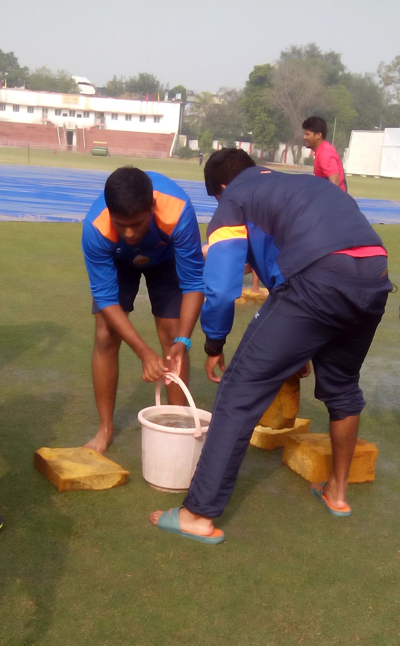 Suryakumar Yadav, with other Mumbai players, helps the groundstaff mop up the outfield, Railways v Mumbai at Delhi, Ranji Trophy, Group A, Karnail Singh Stadium, Delhi, December 15, 2014