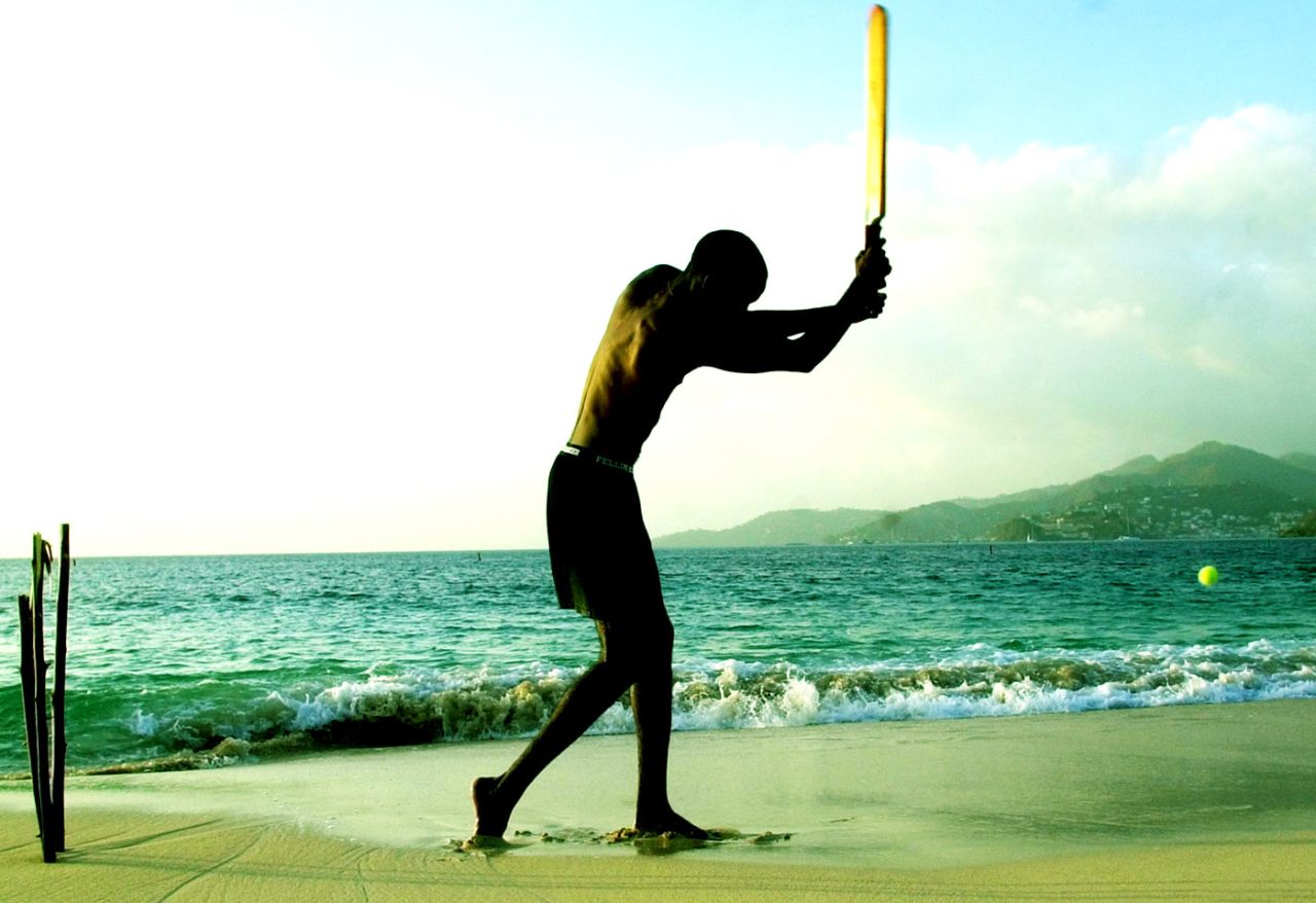A man plays cricket with a tennis ball on Grand Anse Beach in Grenada, May 27, 2003