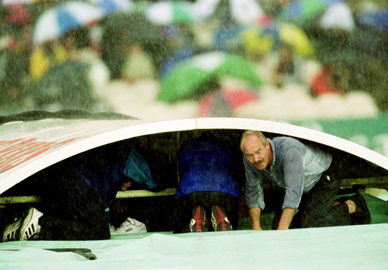 Groundsman Peter Marron takes shelter from the rain during a break in play, England v West Indies, 3rd Test, Old Trafford, 1st day, August 3, 2000 