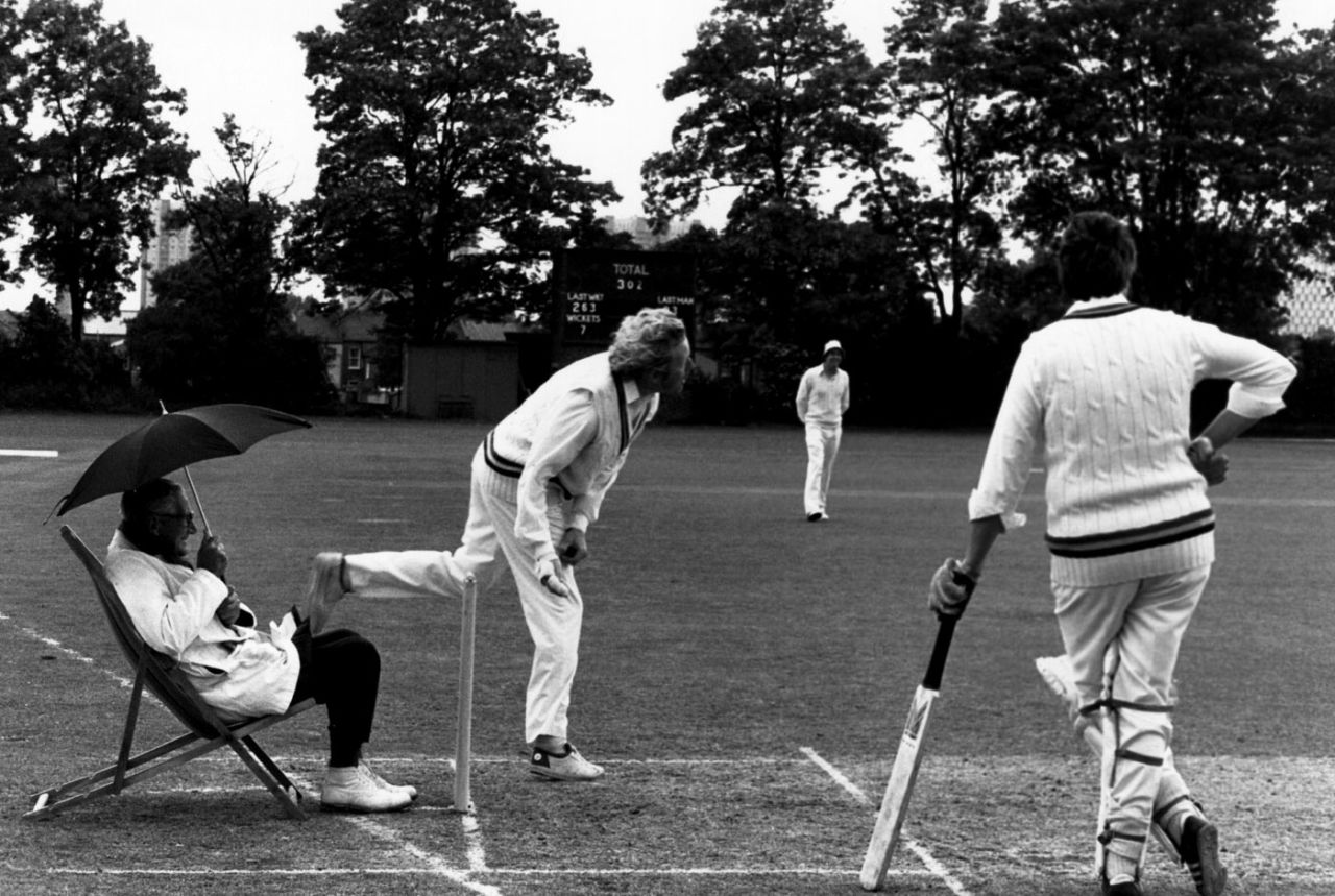 Umpire Percy Lister shelters under an umbrella during a cricket match in Edmonton, June 10, 1980