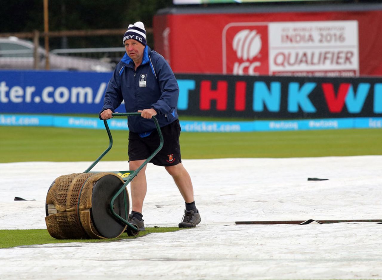 A groundsman works on the covers as rain delayed the start, Hong Kong v Ireland, 3rd place playoff, Dublin, July 26, 2015