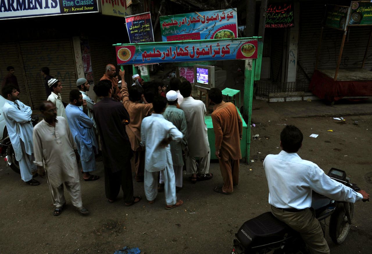 Pakistani fans gather to watch a match between Pakistan and India on a television set on a street in Karachi, Karachi, March 18, 2012