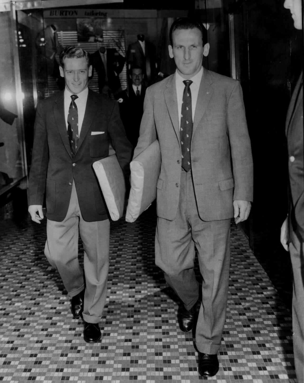 Jackie McGlew and Sid O'Linn walk out of a tailoring store in their new suits, London, September 10, 1960