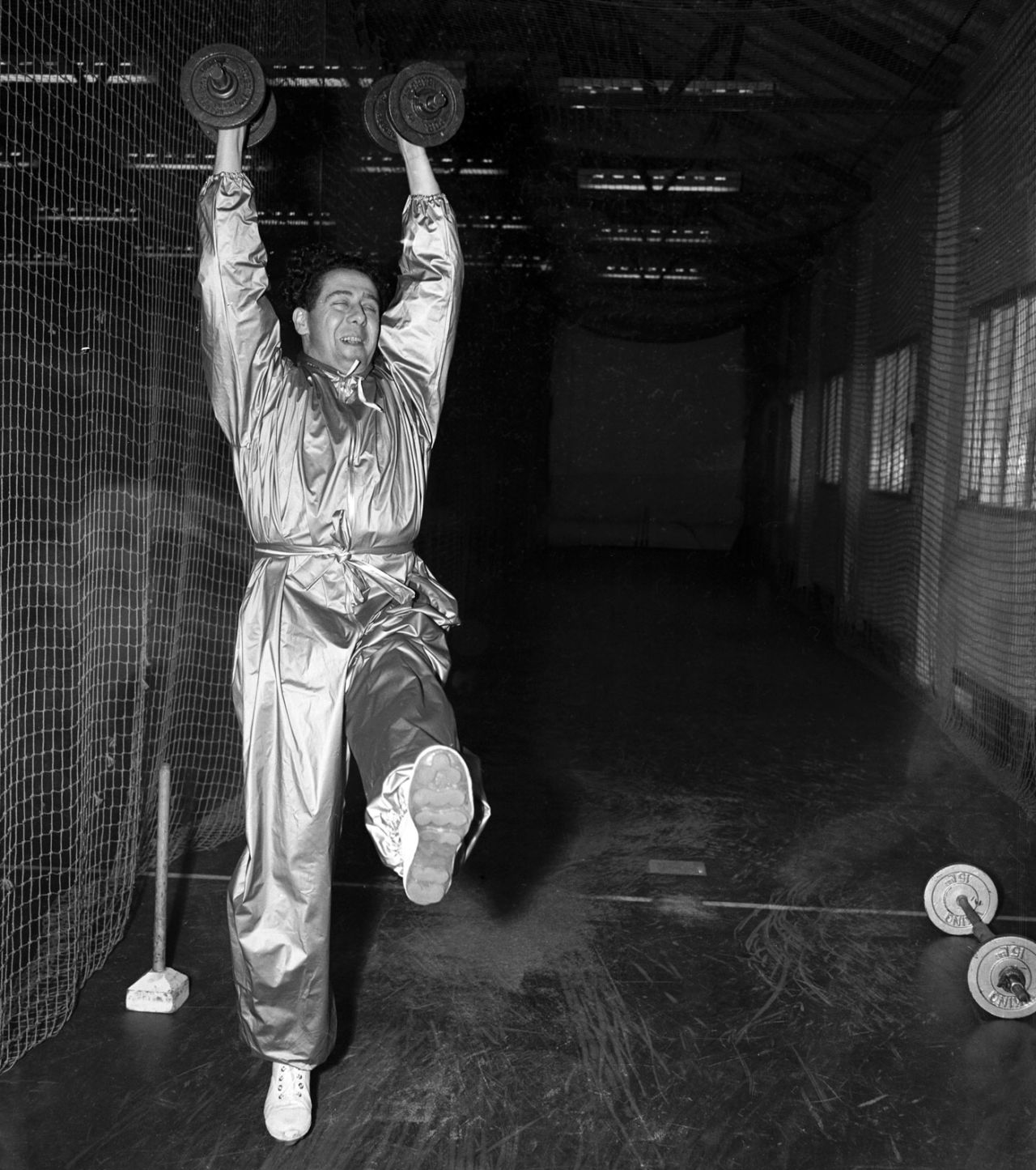 Trevor Bailey exercises while wearing a high-grade plastic sweatsuit designed to help him reduce weight, March 19, 1958