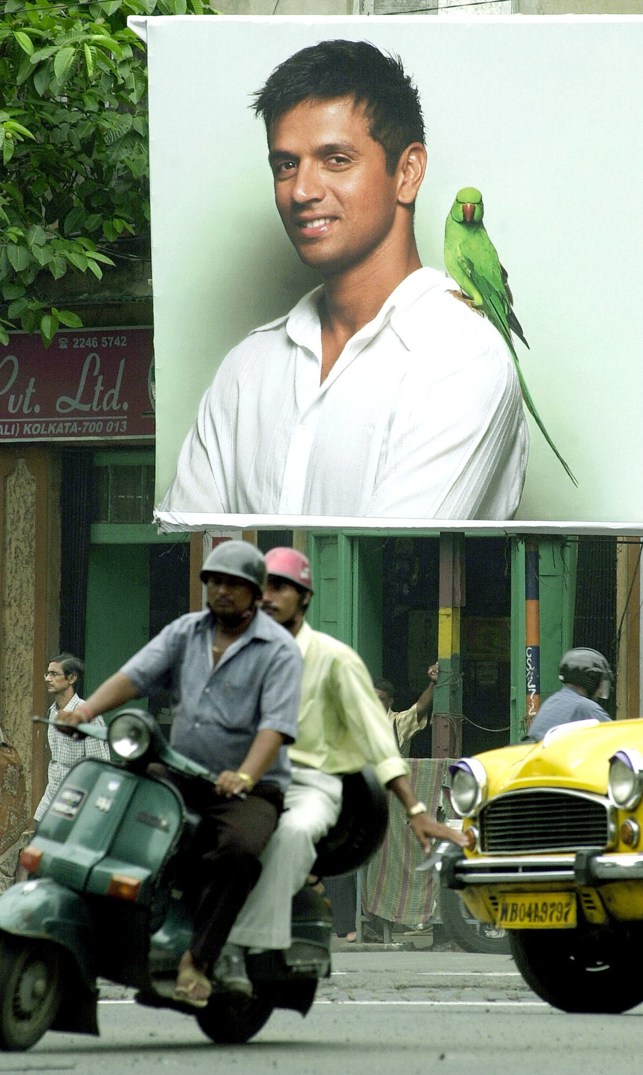 Two men on a scooter ride past a billboard featuring Rahul Dravid, Kolkata,July 16, 2004