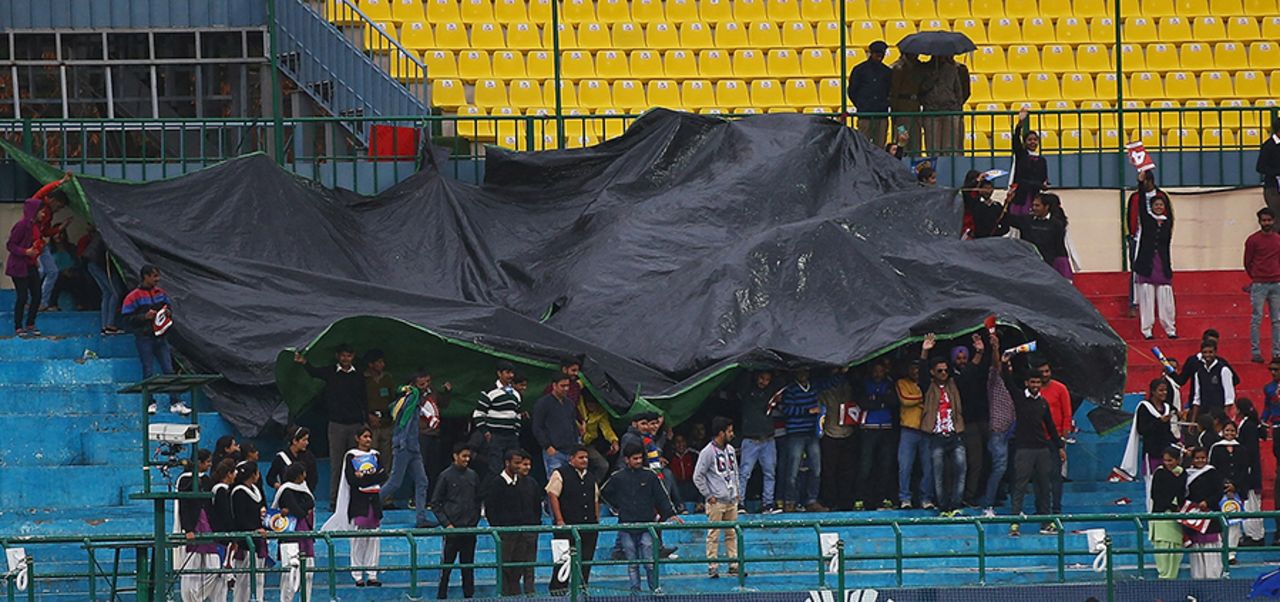 Spectators take cover during a spell of rain, Netherlands v Oman, World T20 qualifier, Group A, Dharamsala, March 11, 2016