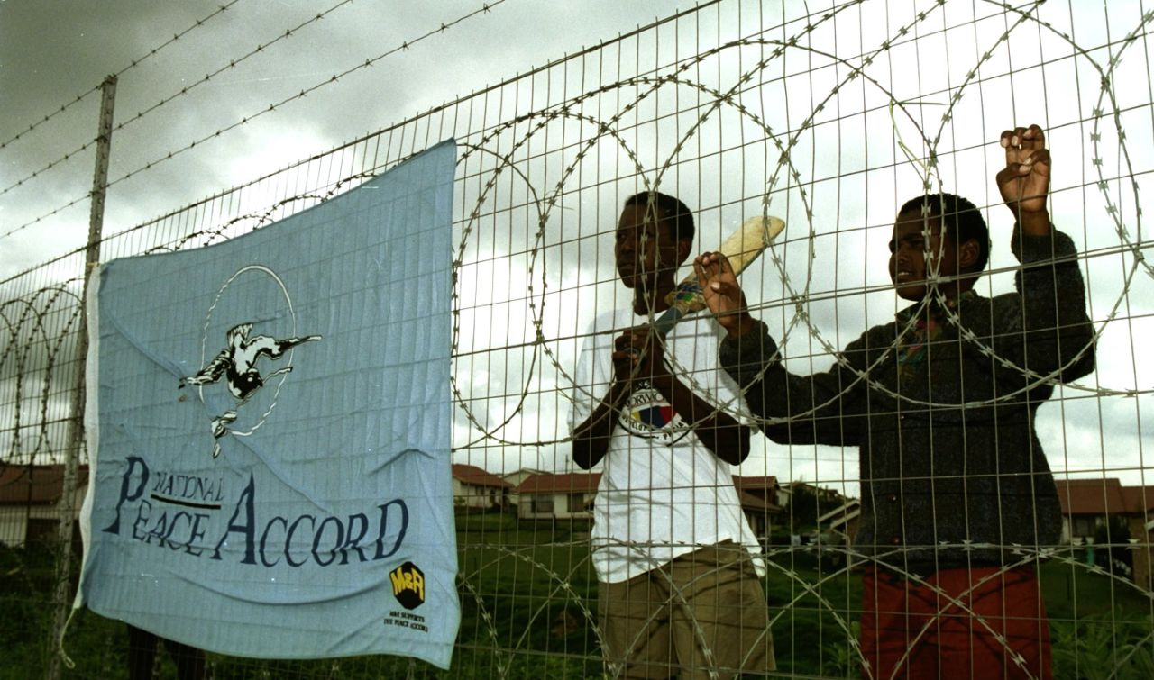 Two boys watch the match between the Transvaal Invitational XI and England A from behind a fence in Alexandra, December 4, 1993