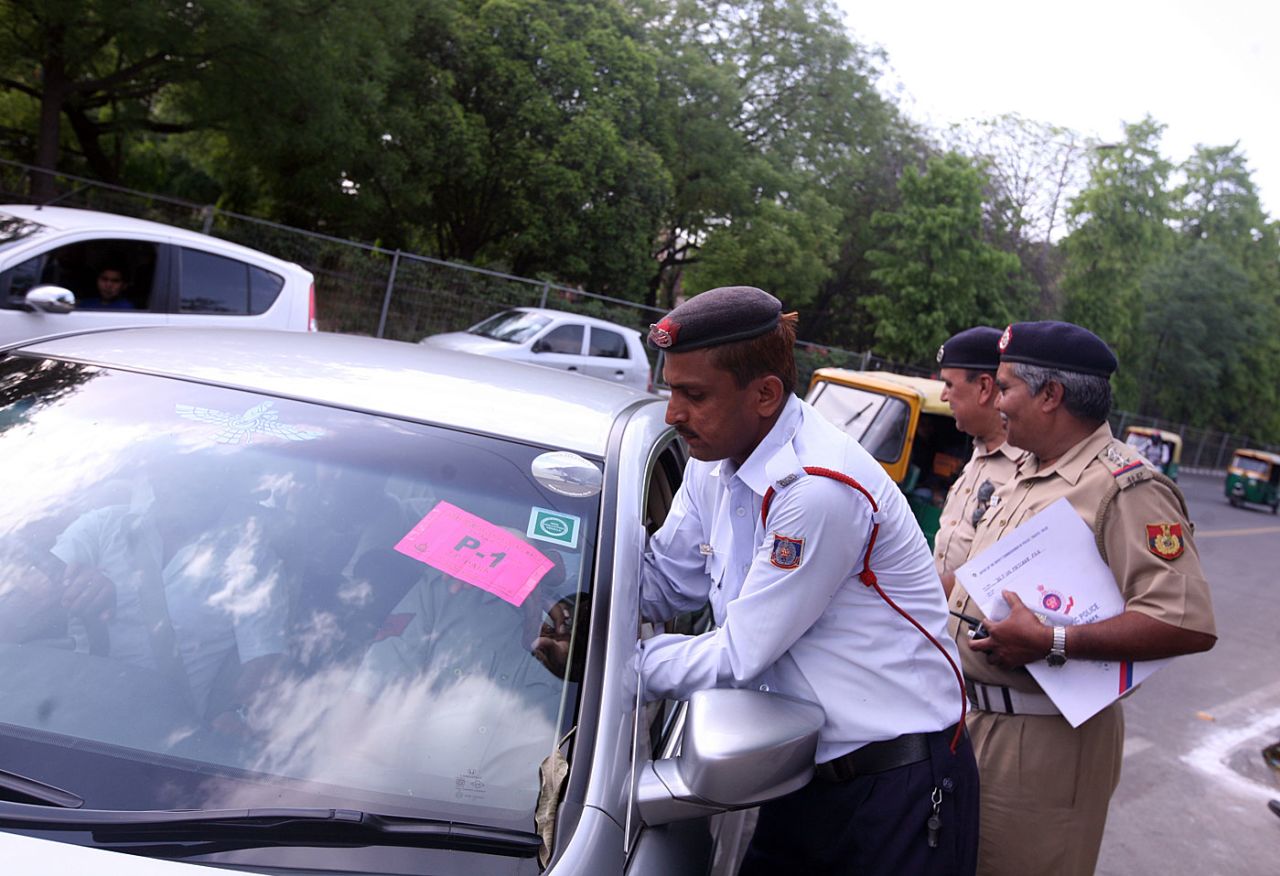 A policeman puts a parking sticker on a car outside the Feroz Shah Kotla, New Delhi, April 19, 2010