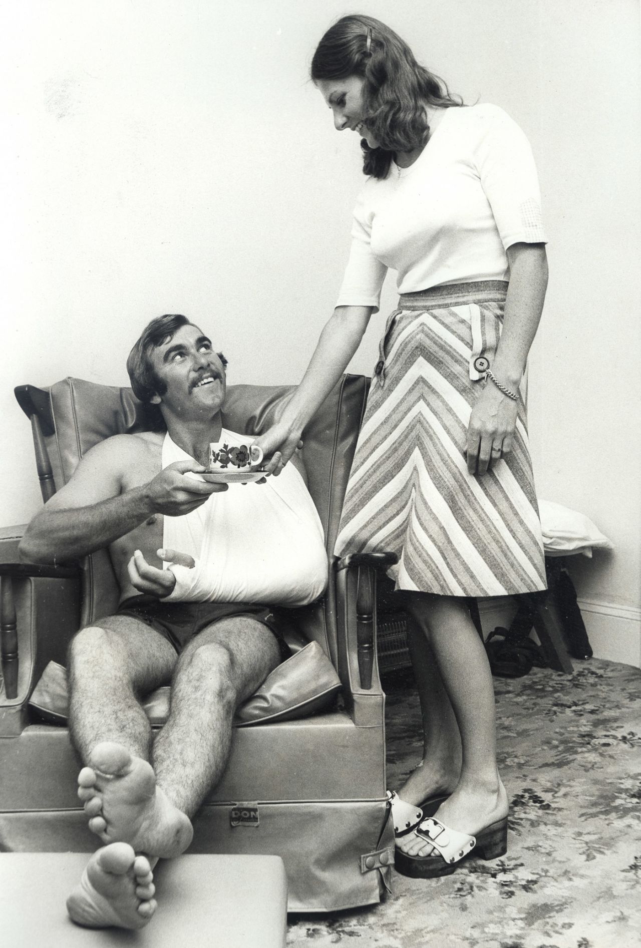 New South Wales opener Len Richardson, whose arm was broken by a Jeff Thomson delivery, gets a cup of coffee from his sister Margaret at their parents' home in Paddington, December 7, 1975