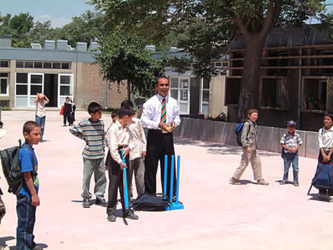 Taj Malik, Afghan National coach (white shirt and tie) giving tips to Khushal Khan High School children using Kwik cricket set donated by ECB