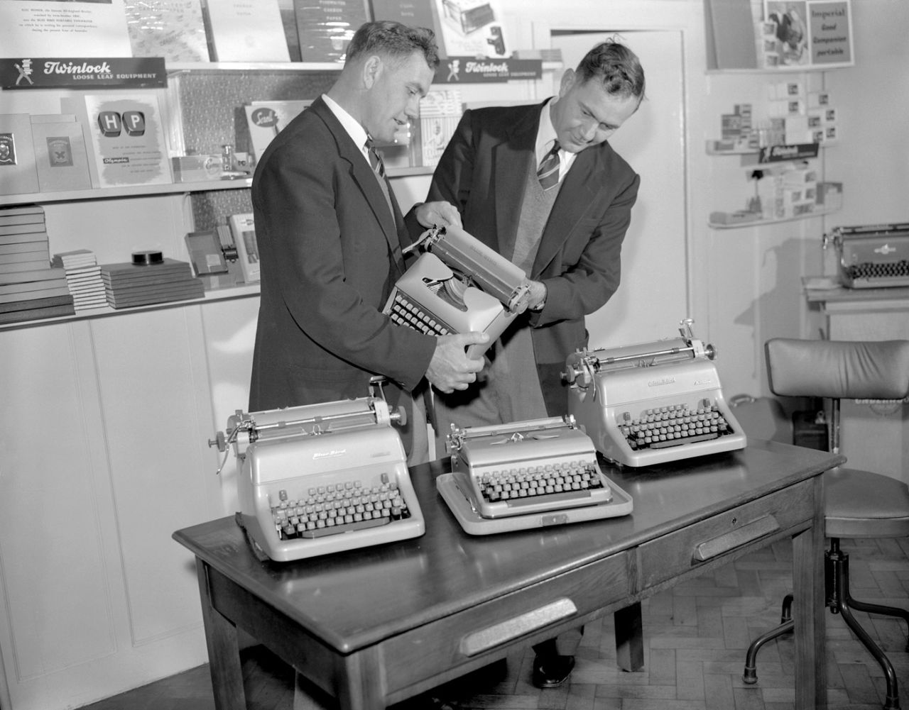 Alec (left) and Eric Bedser look at typewriters in their office equipment store in Woking, October 11, 1955