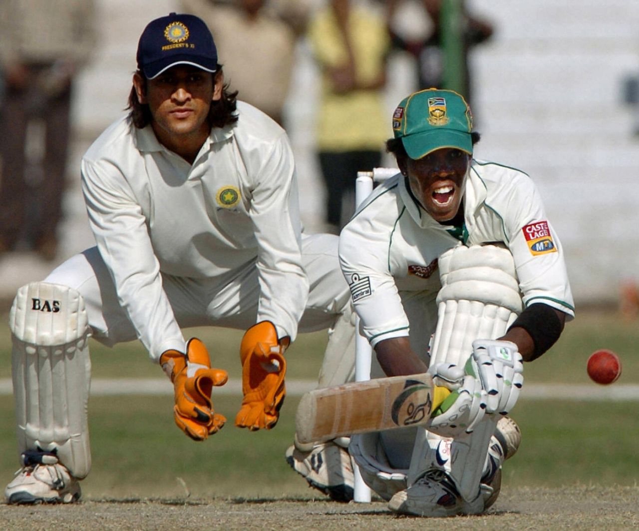 Thami Tsolekile looks to sweep. MS Dhoni watches from behind the stumps, Board President's XI v South Africans, Jaipur, 3rd day, November 16, 2004