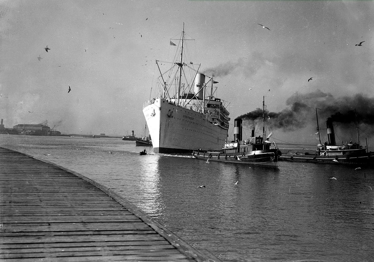 The <i>SS Stratheden</i> being manouvered into port helped by two tugs 