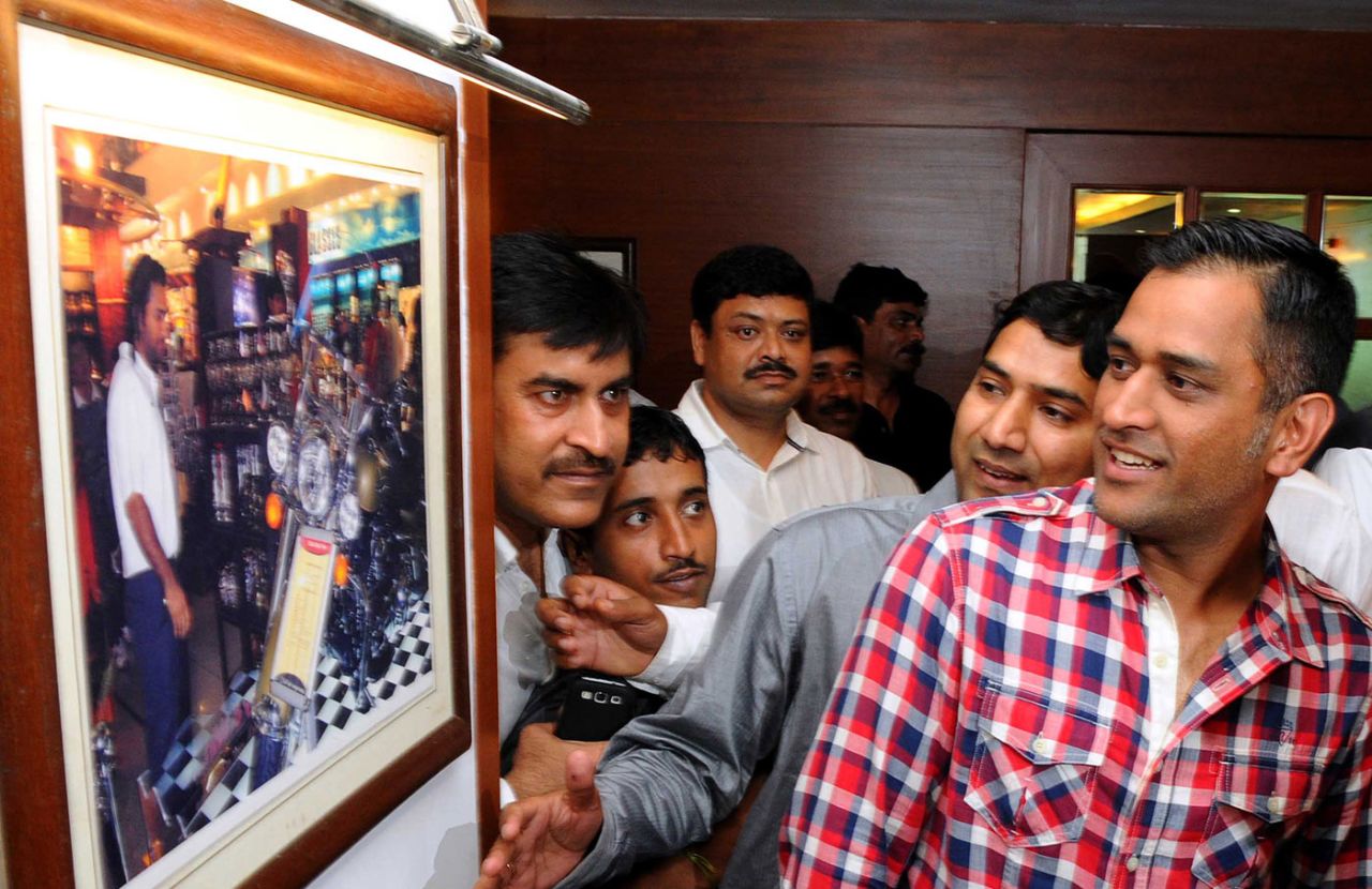 MS Dhoni looks at a photograph of himself at the inauguration of a cricket club, Ranchi, June 21, 2014