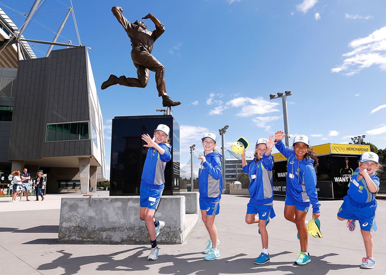 Young fans imitate Dennis Lillee's bowling action under his statue at the MCG, February 18, 2017