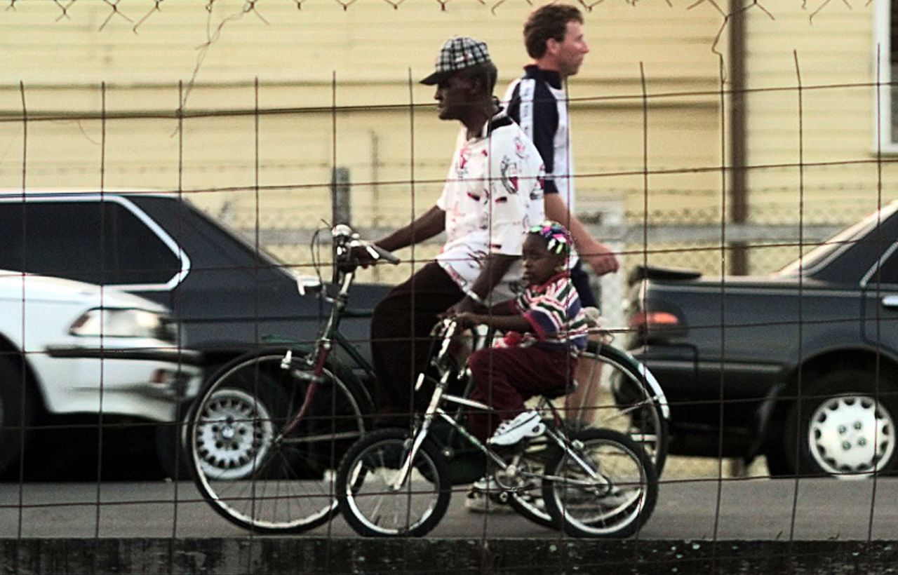 An old man and a child cycle past Mike Atherton in Georgetown, Guyana, February 24, 1998