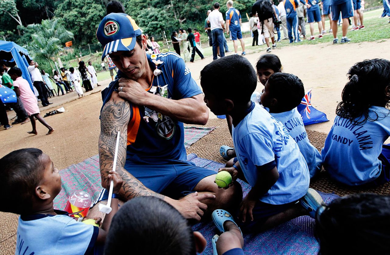 Young children in Kandy examine Mitchell Johnson's tattoos, September 6, 2011