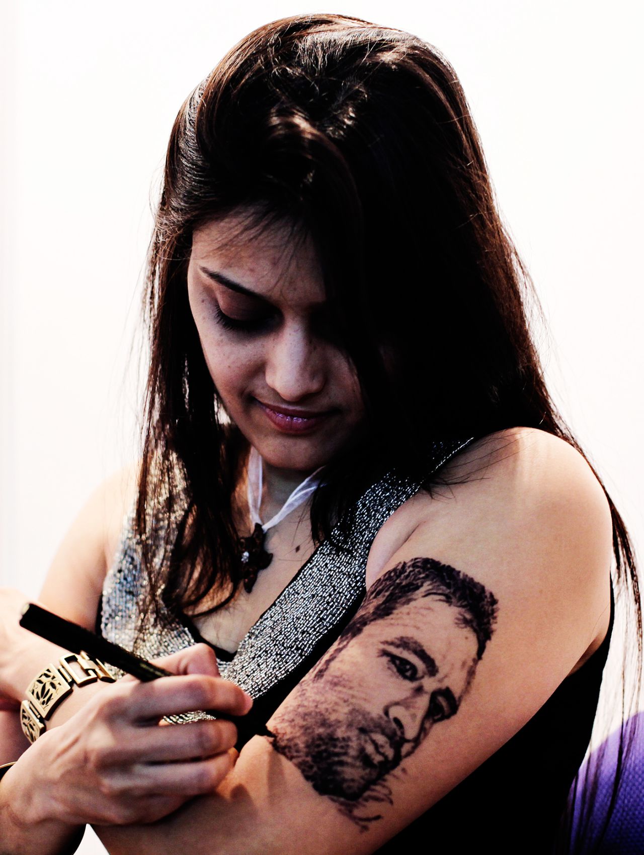 An artist draws MS Dhoni's face on her arm at a tattoo convention in Mumbai, April 9, 2011
