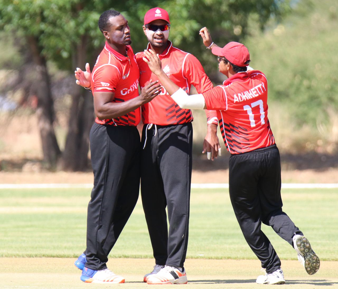 Dilon Heyliger gets hugs from Ruvindu Gunasekera and Bhavindu Adhihetty after taking his first wicket, Canada v Oman, ICC World Cricket League Division Two, Windhoek, February 8, 2018