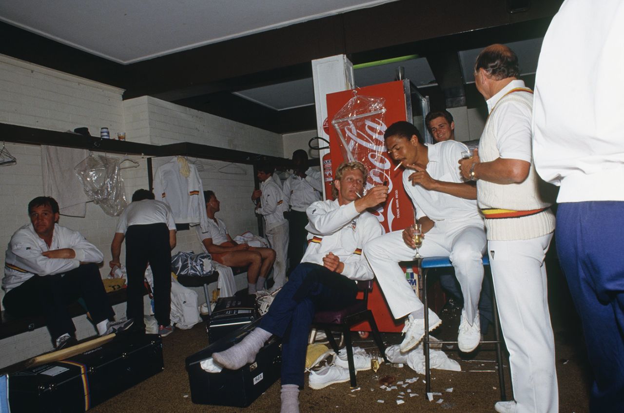 Graham Dilley lights a cigarette for Phil DeFreitas in the dressing room after England's win, Australia v England, first Test, day five, Brisbane, November 19, 1986