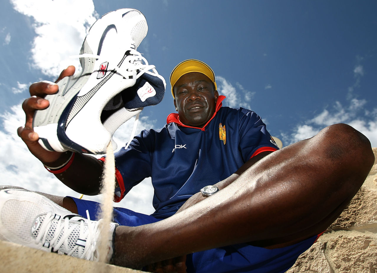 Gladstone Small pours out sand from his shoes during a beach cricket game in Perth, 