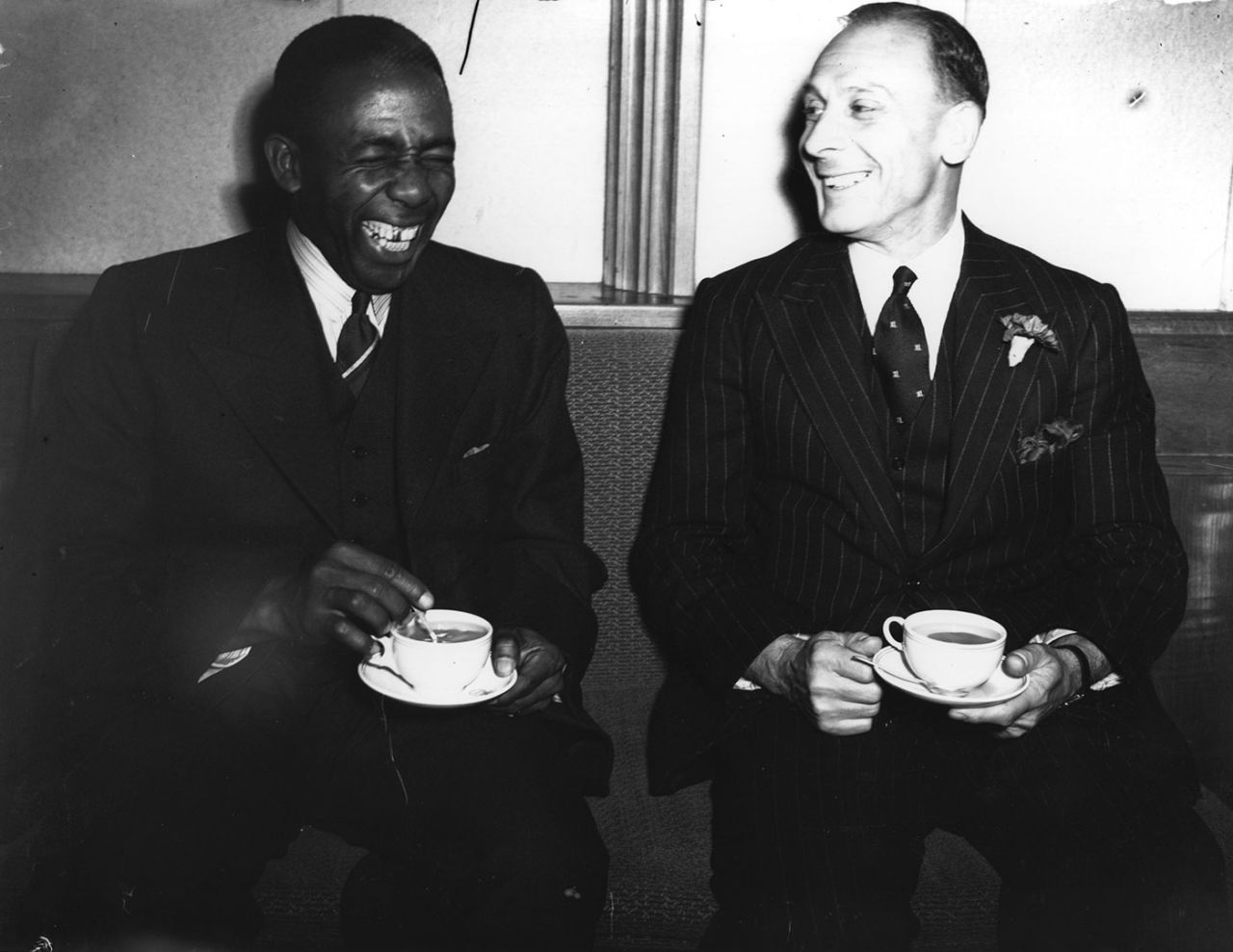 Learie Constantine and Jack Hobbs laugh over cups of tea at a reception to welcome the West Indies team, London, June 23, 1939