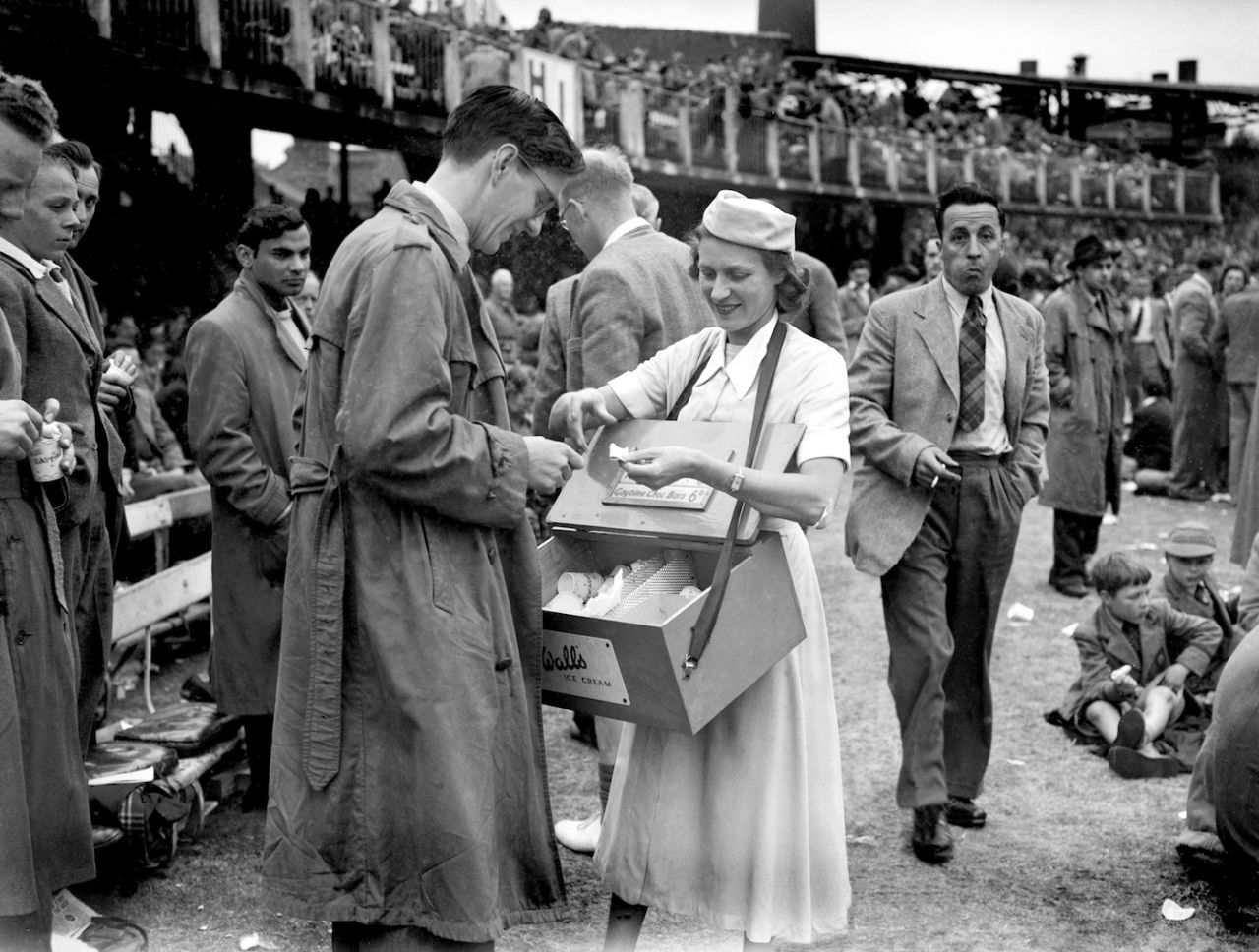 A woman sells Wall's ice cream to a spectator during the interval, day three, second Test, England v India, June 21, 1952