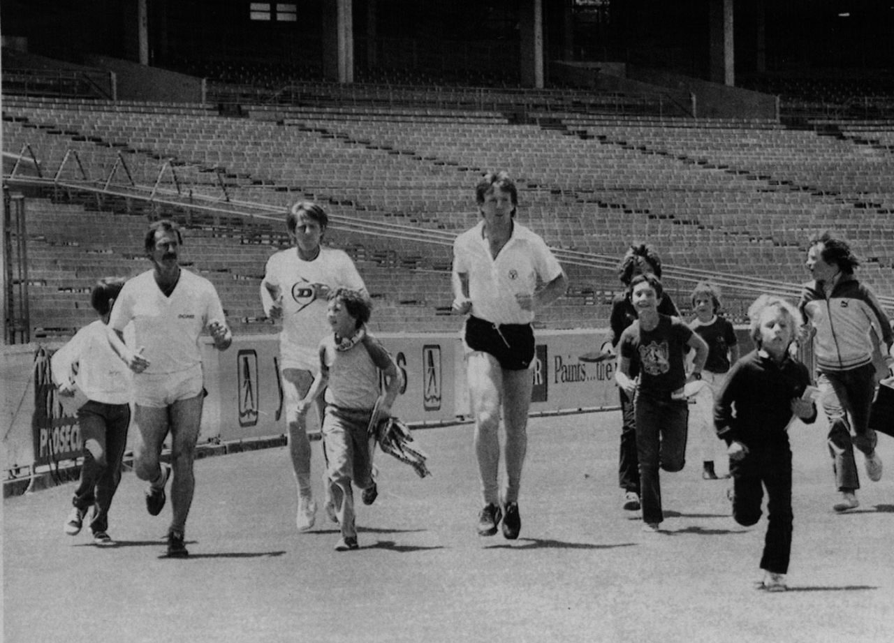 Dennis Lillee, Jeff Thomson and Geoff Lawson jog around the MCG with kids following them around, Melbourne, December 1981