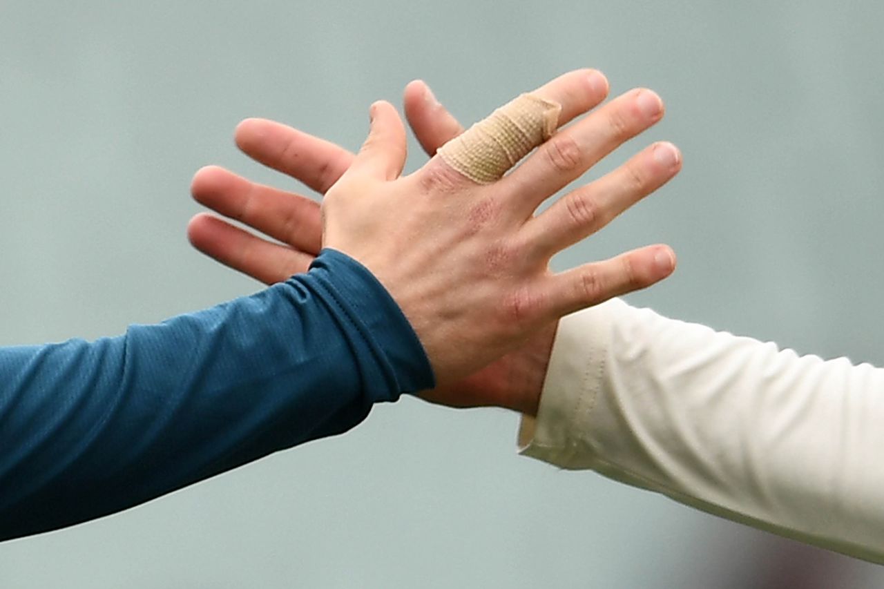A close up of Tim Paine's bandaged right index finger as he shakes hand with Nathan Lyon, Australia v India, first Test, Adelaide, December 10, 2018