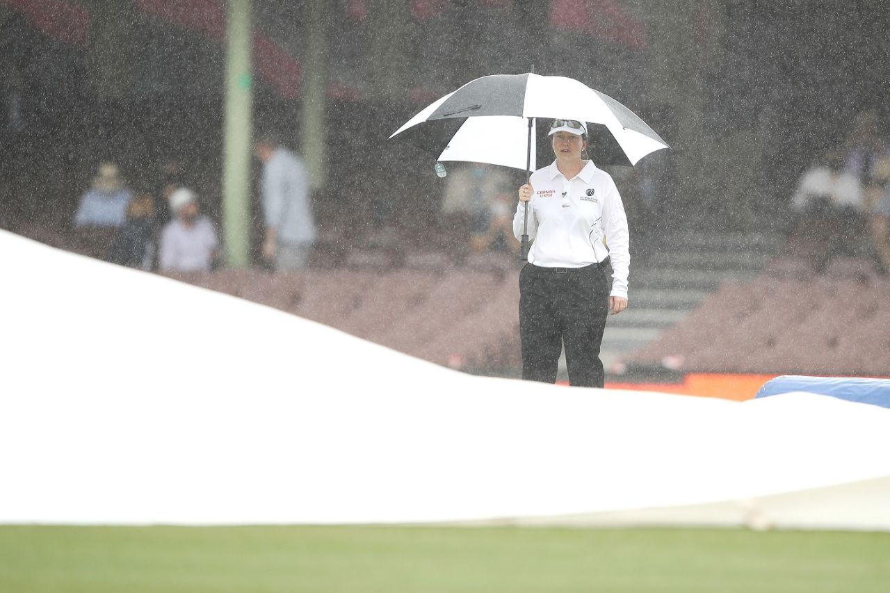 Reserve umpire Claire Polosak watches on as ground staff cover the pitch during a rain delay, Australia vs India, 3rd Test, Sydney, 1st day, January 7, 2021