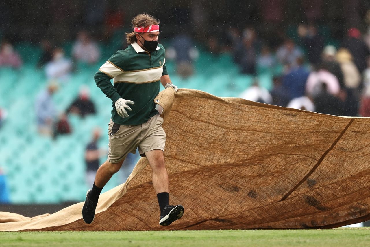 A groundsman covers the pitch as rain delays play, Australia v India, 3rd Test, Sydney, 1st day, January 7, 2021