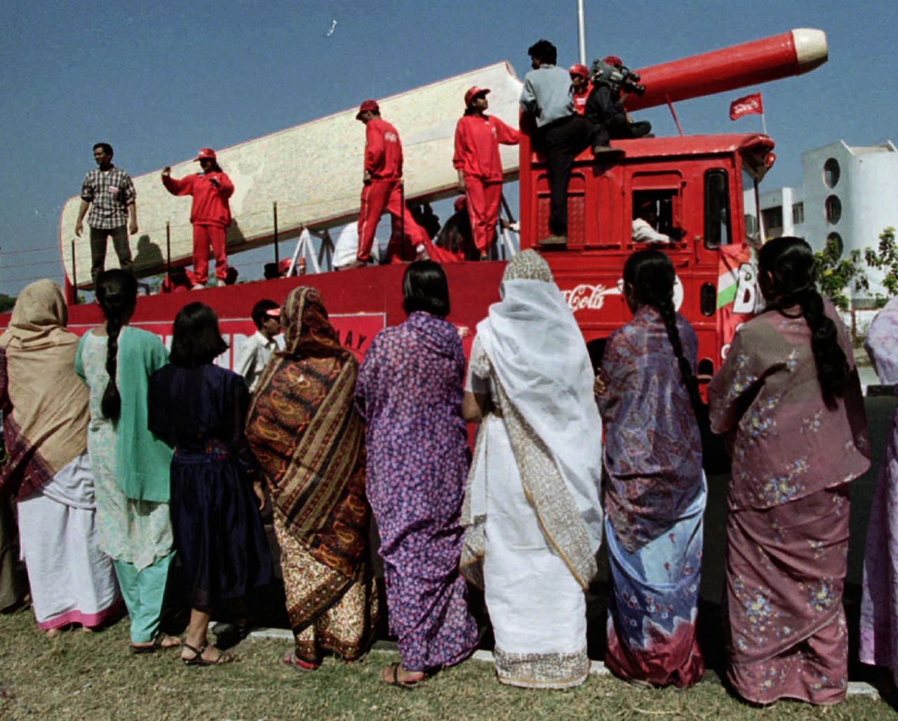 Women in Calcutta watch a giant bat being driven past in a parade for the World Cup, February 10, 1996