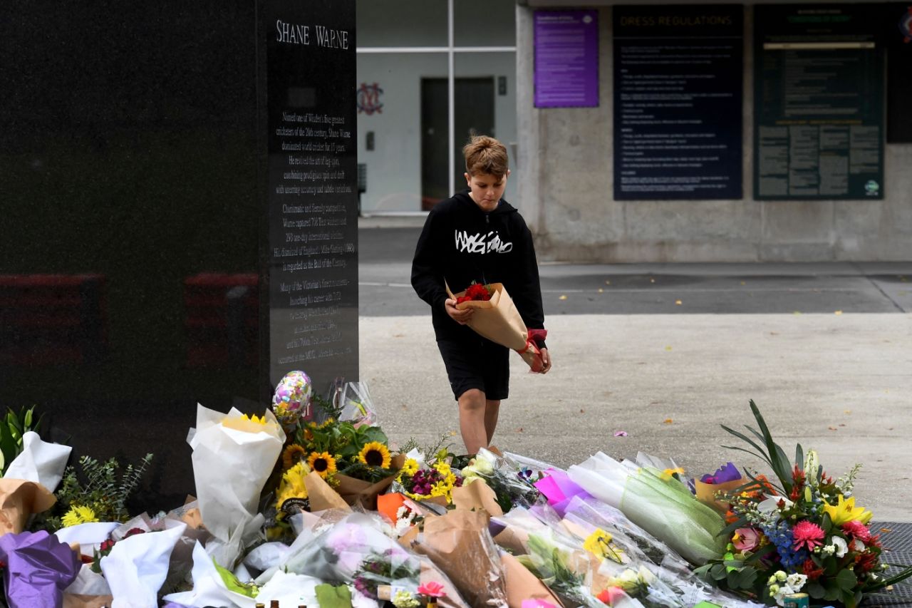 A fan lays a bouquet at Shane Warne's statue outside the MCG, Melbourne, March 6, 2022