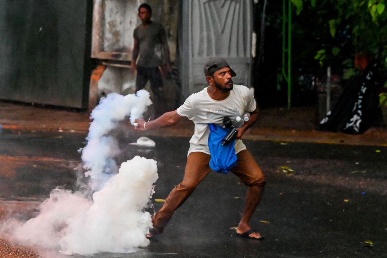 A protester throws back a tear gas canister fired by police to disperse an anti-government protest, Colombo, May 29, 2022