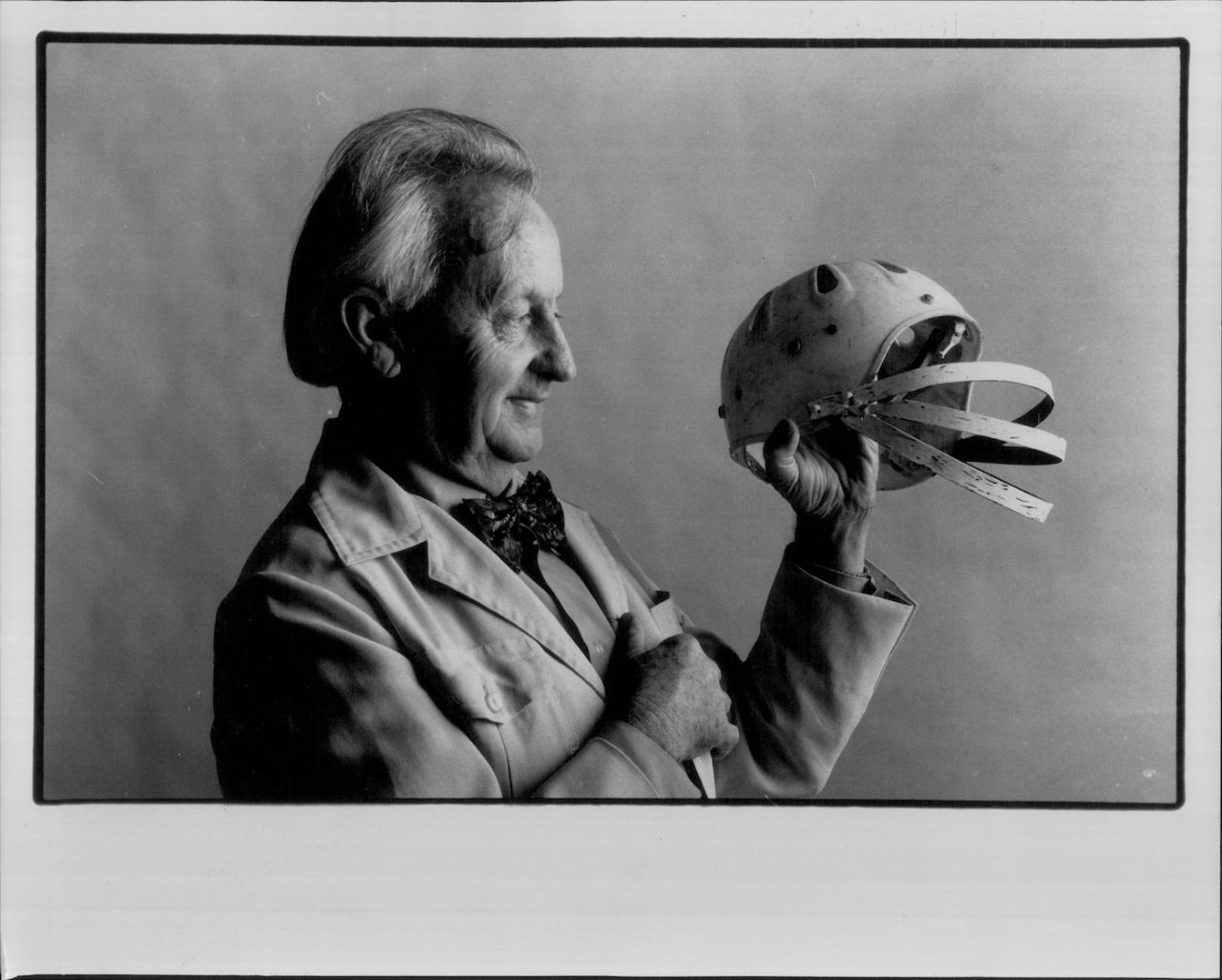 Bruce Miles demonstrates his design for a cricket helmet, March 1, 1955