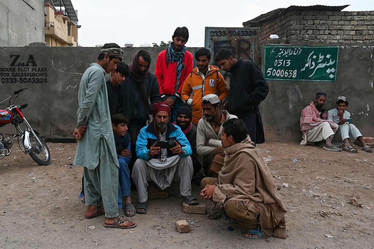 Labourers watch the final on a mobile phone along a street in Rawalpindi, Rawalpindi, November 13, 2022