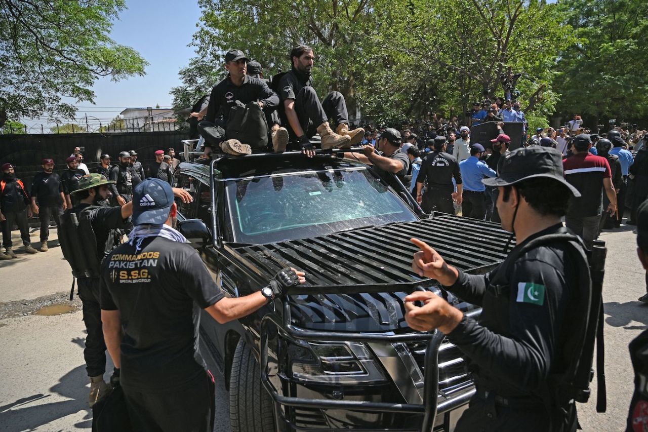 Security personnel escort a car carrying Imran Khan as he arrives at the high court in Islamabad, May 9, 2023