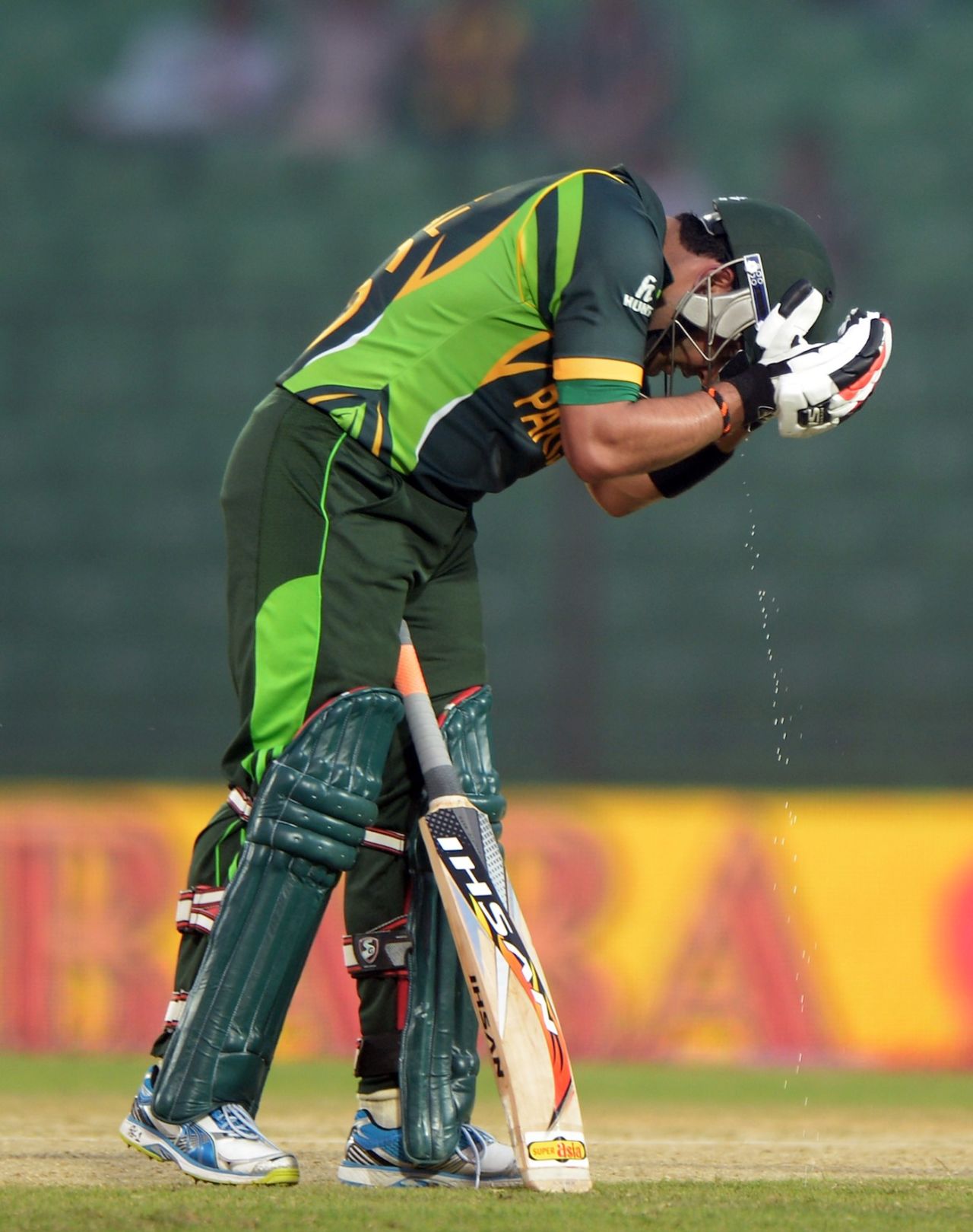 Umar Akmal drains his helmet of sweat, Afghanistan vs Pakistan, Asia Cup 2014, Fatullah, February 27, 2014