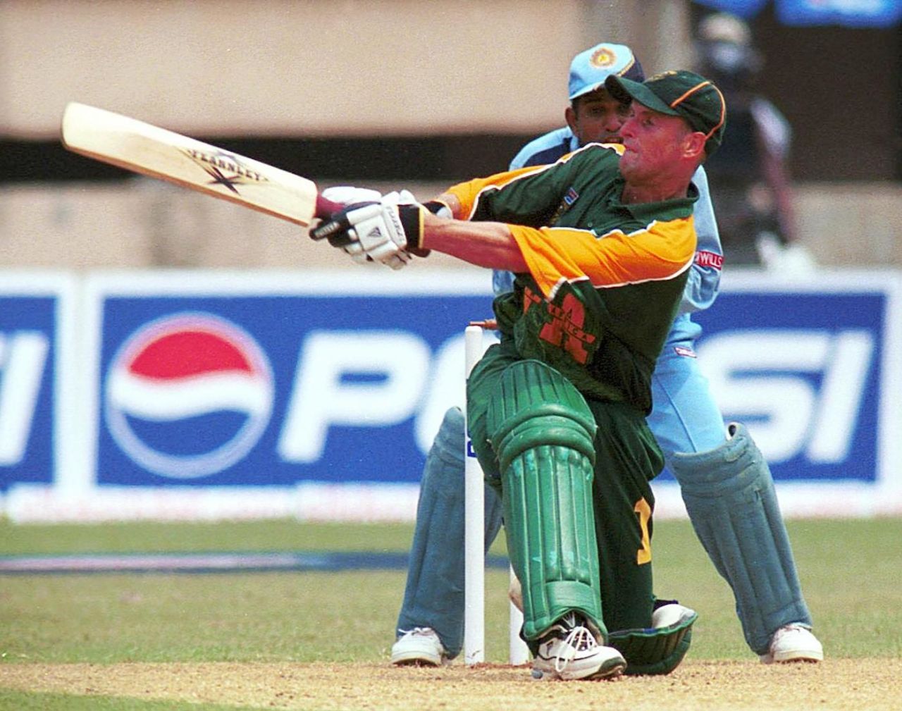 South African batsman Gary Kirsten sweeps a ball on his way to making 115 runs as Indian wicketkeeper Samir Dighe (partly covered) looks on during the first one-day international cricket match between India and South Africa in Cochin 09 March 2000.