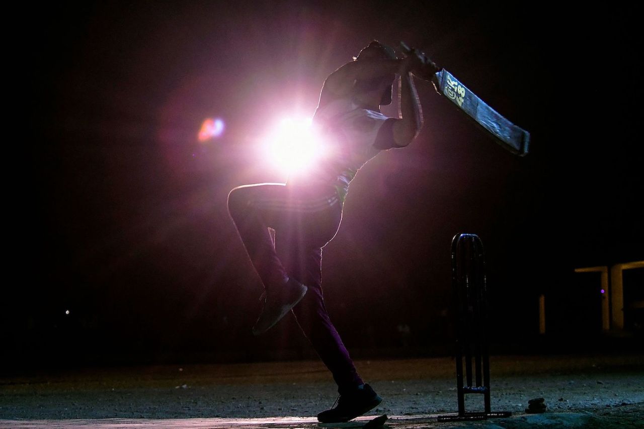 An improvised floodlight dramatically lights up a player in a tape-ball match, Karachi, April 7, 2023