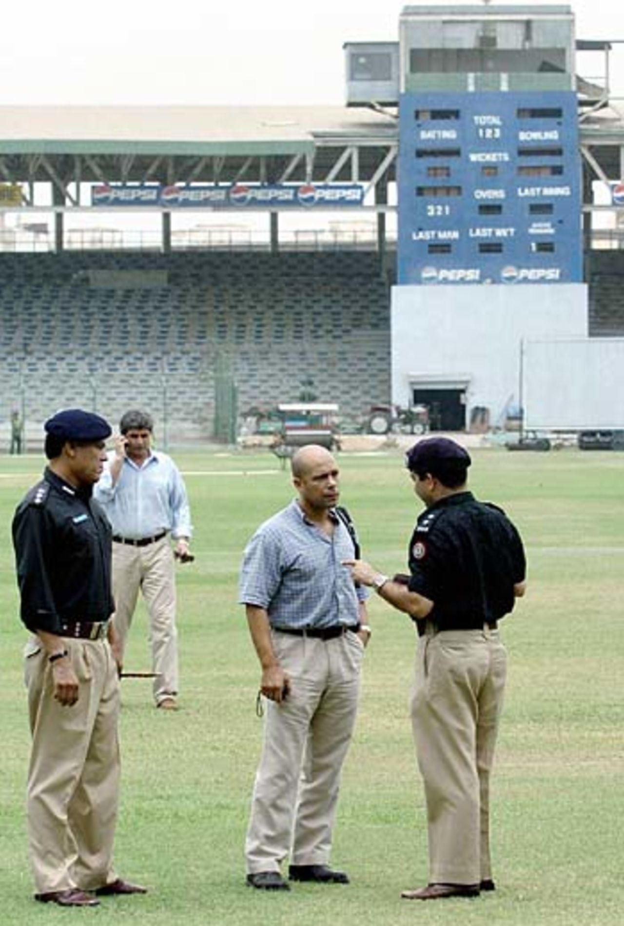 English security expert Andy Allman listens to a Pakistani police officer as he visits Karachi's National Stadium, June 28, 2005