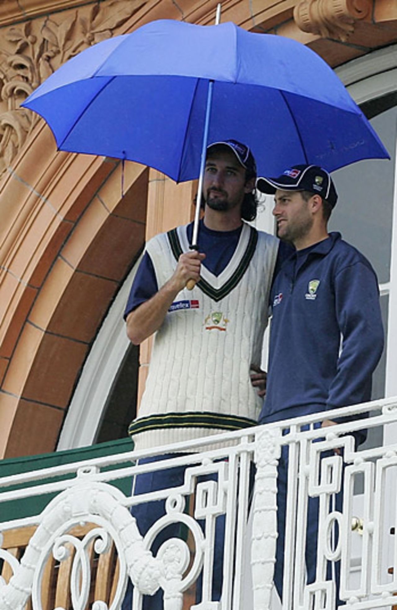 Jason Gillespie and Simon Katich shelter under an umbrella, as rain delays the fourth day's play at Lord's, England v Australia, July 24, 2005